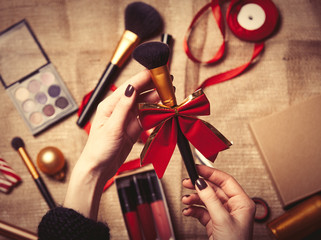 hands are wrapping cosmetics in christmas gifts