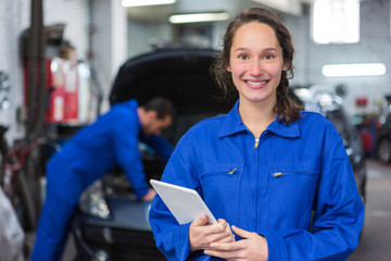 Young attractive woman mechanic working at the garage - obrazy, fototapety, plakaty