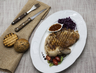 Juicy roast chicken with vegetables and ketchup. Served on porcelain plate on a tablecloth with fork and knife . Fried chicken tapaka, tobacco.