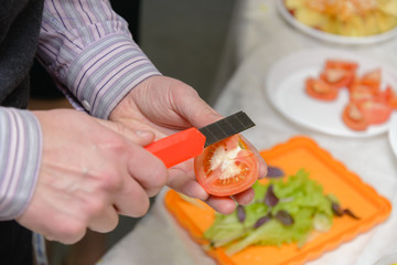 Man in the office cut a tomato with a box cutter	