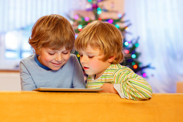 Two happy little kids playing with tablet pc, indoors
