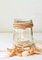 
Votive candles tea light in jars with sea sand, sea shells. Marine style home accessories for beach themed interior decorating