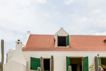 Fototapeta na wymiar Red Tile Roof and Green Shutters on White Plaster