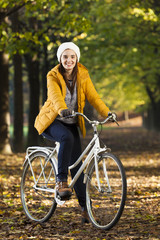 Fototapeta na wymiar Smiling woman standing with a vintage bicycle at the park