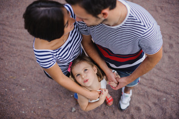 Parents with child stand having joined hands