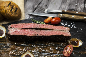 Ribeye steak from marble beef meat with vegetables and barbecue sauce. Served on a plate of black stone with fork and knife .