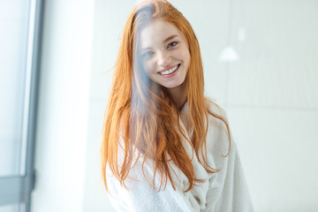 Redhead woman in bathrobe looking at camera