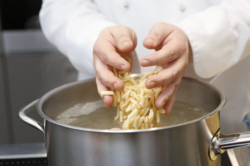 Mani di un cuoco che cucinano della pasta