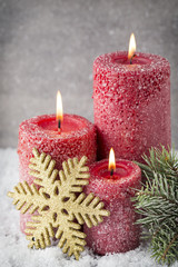 Obraz na płótnie Canvas Three red candles on gray background, Christmas decoration. Adve