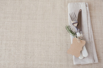 Table place setting with rosemary and empty tag, holidays copy space, selective focus, vintage tone