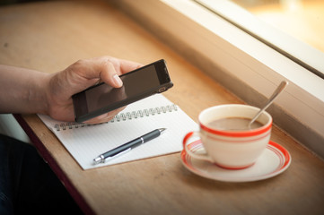 using smart phone with coffee cup