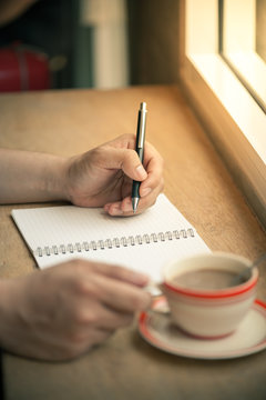 writing on notebook with coffee cup