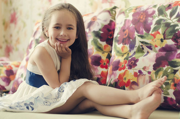 Portrait of cute girl sitting barefoot in the bed