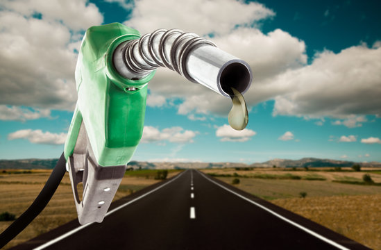 Green gas pump with one last drop and the road on the background