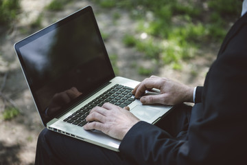 Businessman using a laptop sitting at the park