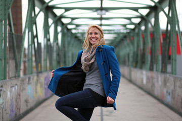Blonde woman in blue coat on a bridge