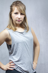 Kobieta w studio z blond włosami, ubrana na sportowo w luźny, szary t-shirt.
