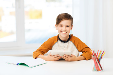 Naklejka premium smiling boy with tablet pc and notebook at home