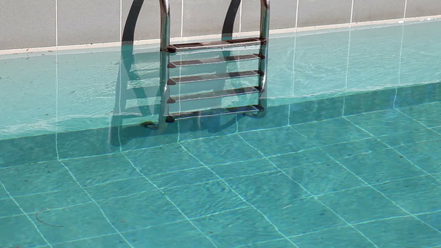 Water splashing in the outdoor swimming pool with ladder