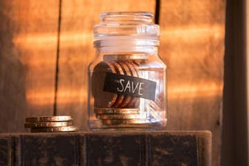 Save idea, gold coins in a glass jar,  inscription save and a stack of gold coins on the sunset.