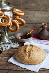 Russian rustic still life: a samovar with bagels and homemade bread with flax seeds. Selective focus. Toned