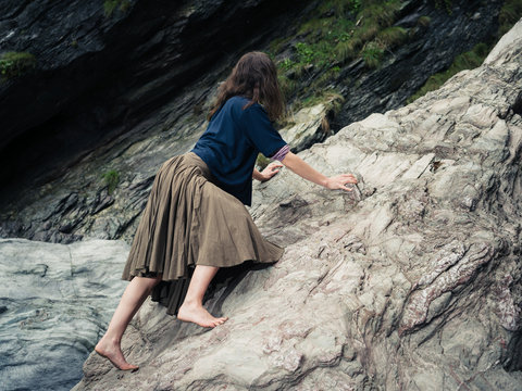 Young barefoot woman climbing rocks