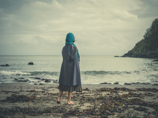 Young barefoot woman with headscarf on beach