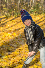 Boy playing with yellow leaves in autumn park