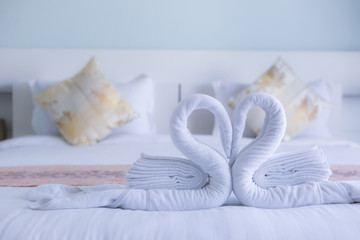 Fototapeta na wymiar white swan twisted towel heart shape on white bed ofr honeymooners, soft focus