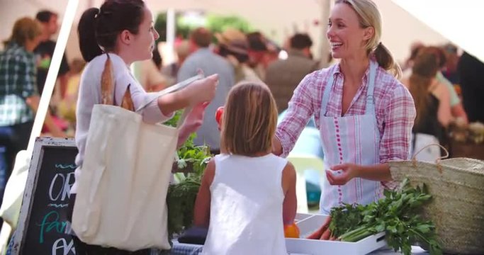 Mother and daughter buying vegetables at a market stall