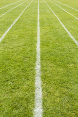 Running track lines marked on the grass on a sports field.