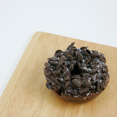The dark chocolate donut (doughnut) on the wooden board.