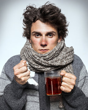 Man Cold / Ill young man with red nose, scarf, sneezing into handkerchief. Medication or drugs abuse, healthcare concept