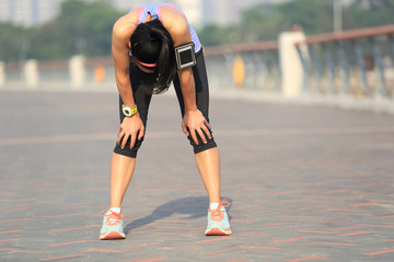 tired woman runner taking a rest after running hard on sunshine seaside