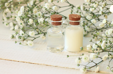 Fototapeta na wymiar Glass vials with skincare cosmetic product, flower background. Botanical cream and tonic.