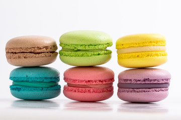 six colourful French macarons on white background, lying on top of each other