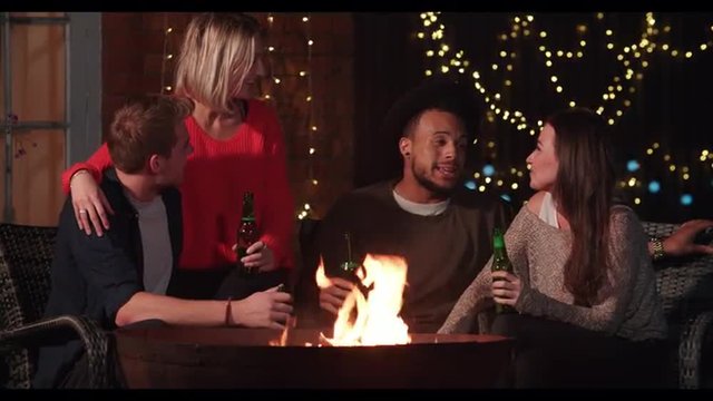 Group Of Friends Enjoying Evening Drinks By Firepit