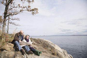 Fototapeta na wymiar Mature couple reading a map near lake