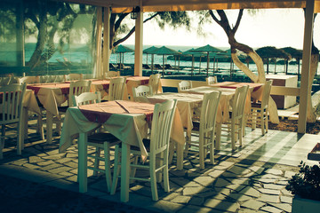 traditional greek outdoor restaurant on terrace overlooking Mediterranean sea (Greece ).  toned image