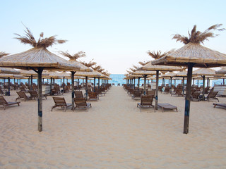 Beach chairs and umbrella on the sand near sea, blue sky