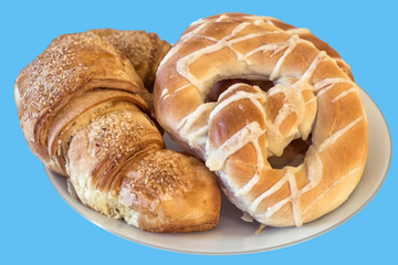 Croissant Puff Pastry Sprinkled with Sesame Seeds and Pretzel Isolated on Blue Background.