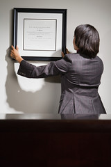 Business woman hanging framed certificate