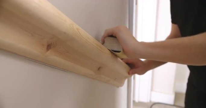 Close-up of decorator’s hands sanding a wooden handrail