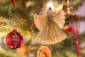 Selbst gebastelter Weihnachtsengel aus Holz und Papier an dekoriertem Tannengrün