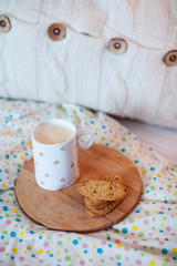 Coffee and cookies on a bed with pillows