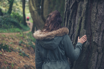 Young woman in winter coat by tree