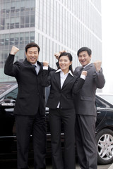 Three businesspeople outdoors cheering