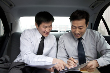 Businessmen working in back of car