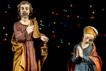 Fototapeta premium Saint Joseph and Mary Virgin with colorful stars at background. Nativity scene figures. Christmas traditions.