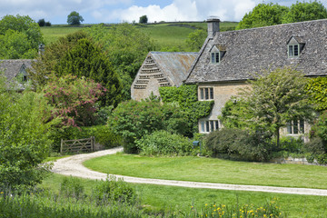 Sandy road in a rural village with old traditional english stone cottages in a green valley
